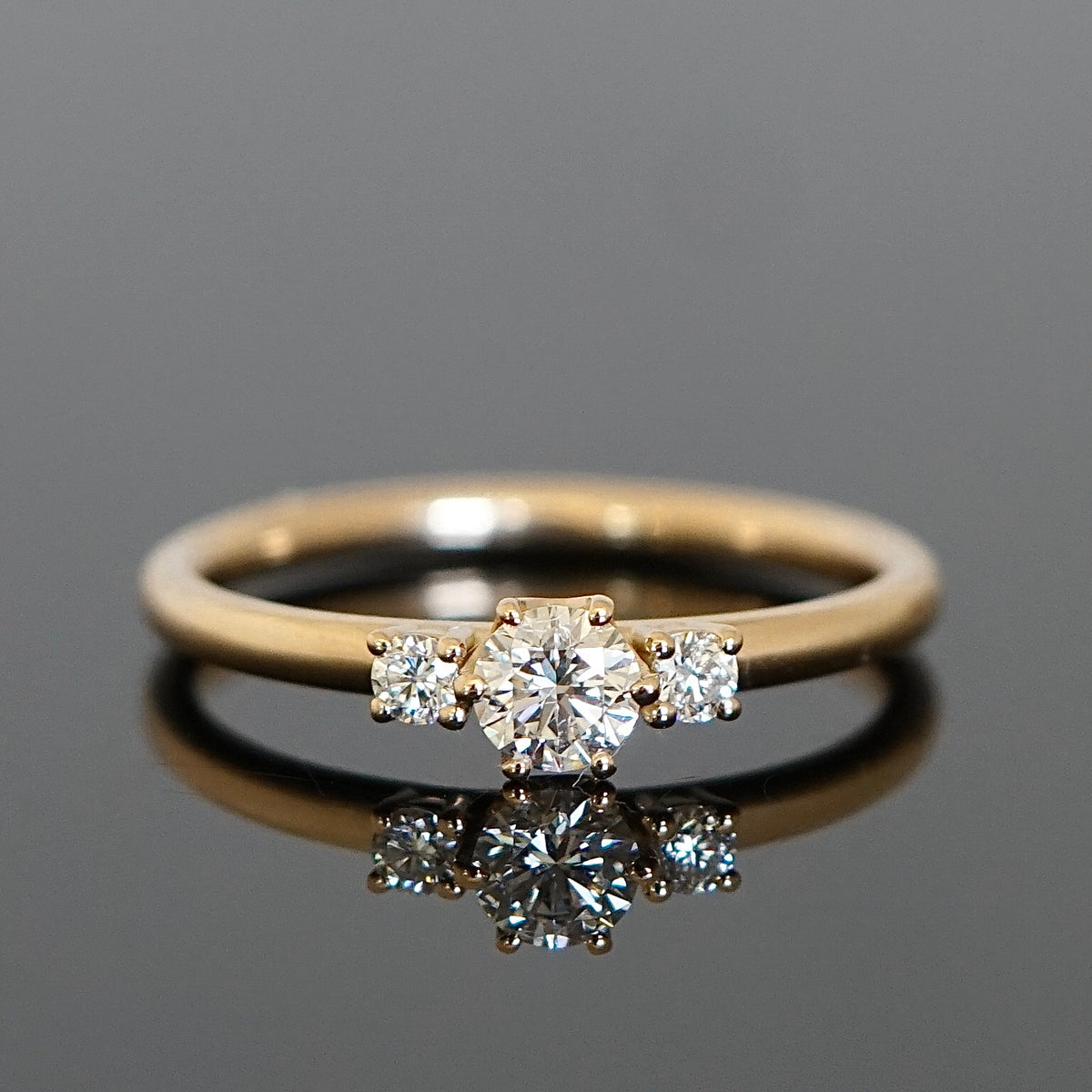 Verlobungsring Mittelstein 0,25 Ct., umgeben von 2 kleineren Diamanten