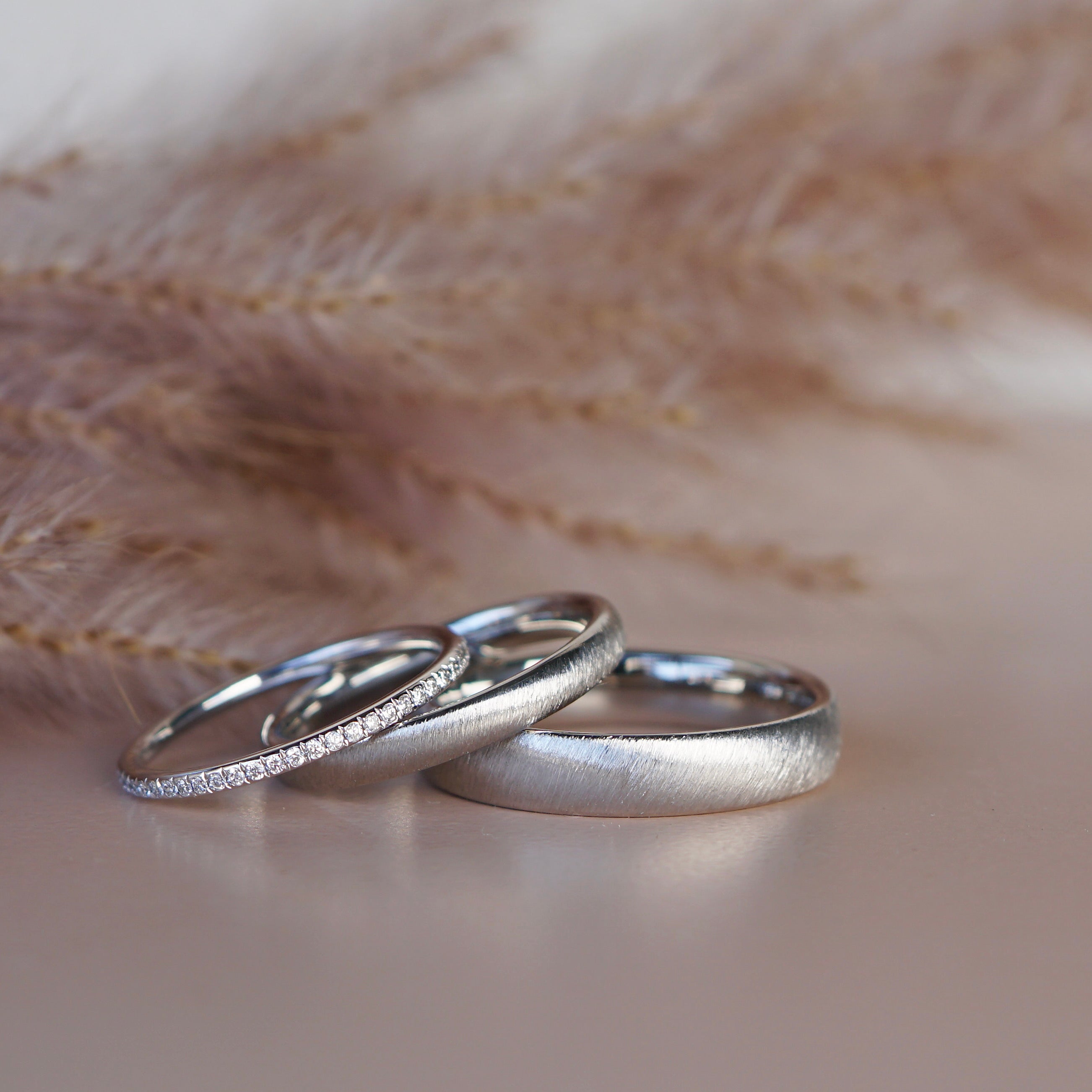 Eheringe mit samtiger Oberfläche und Diamantring aus Platin.