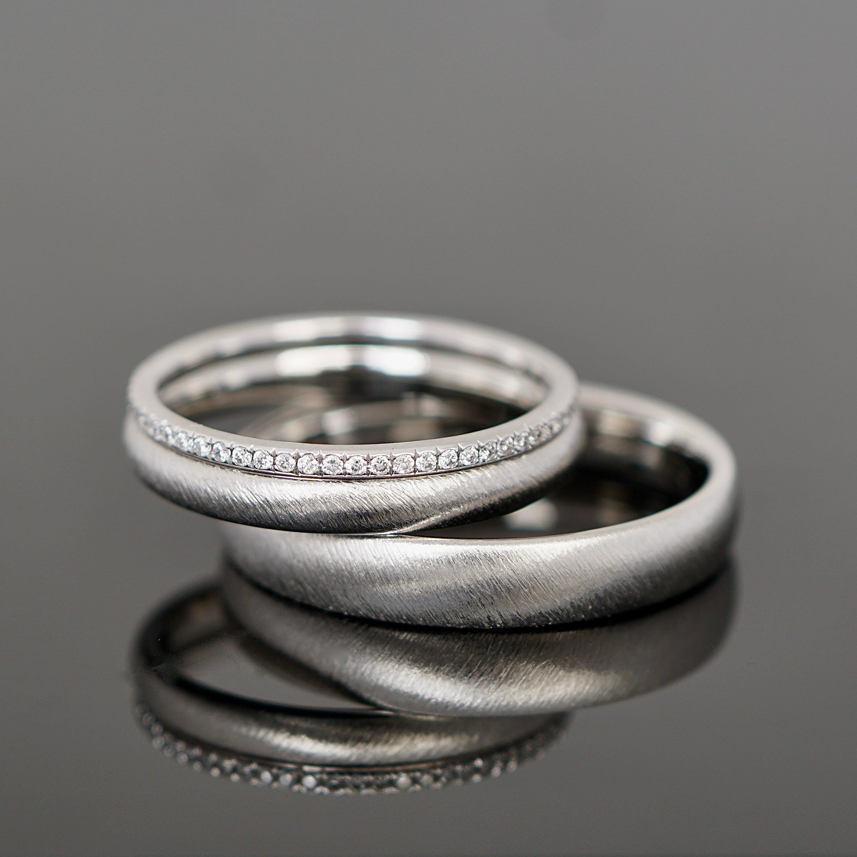 Gebürstete Eheringe aus Platin mit einem Brillantring als Vorsteckring.