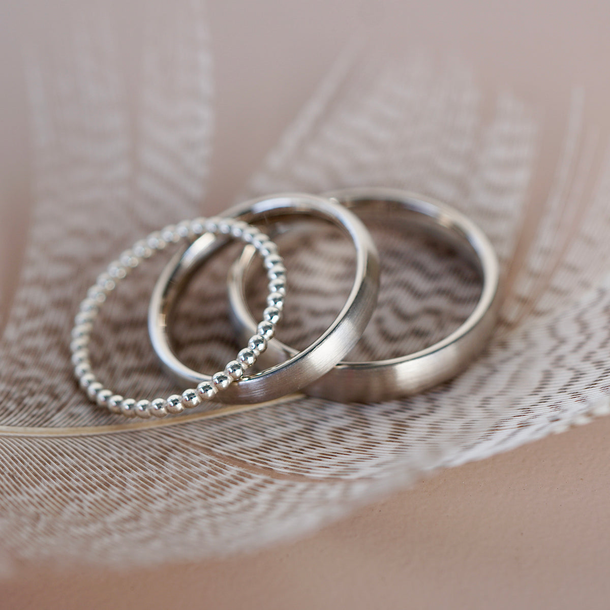 Eheringe Set aus Weißgold mit Zusteckring in einer Feder.