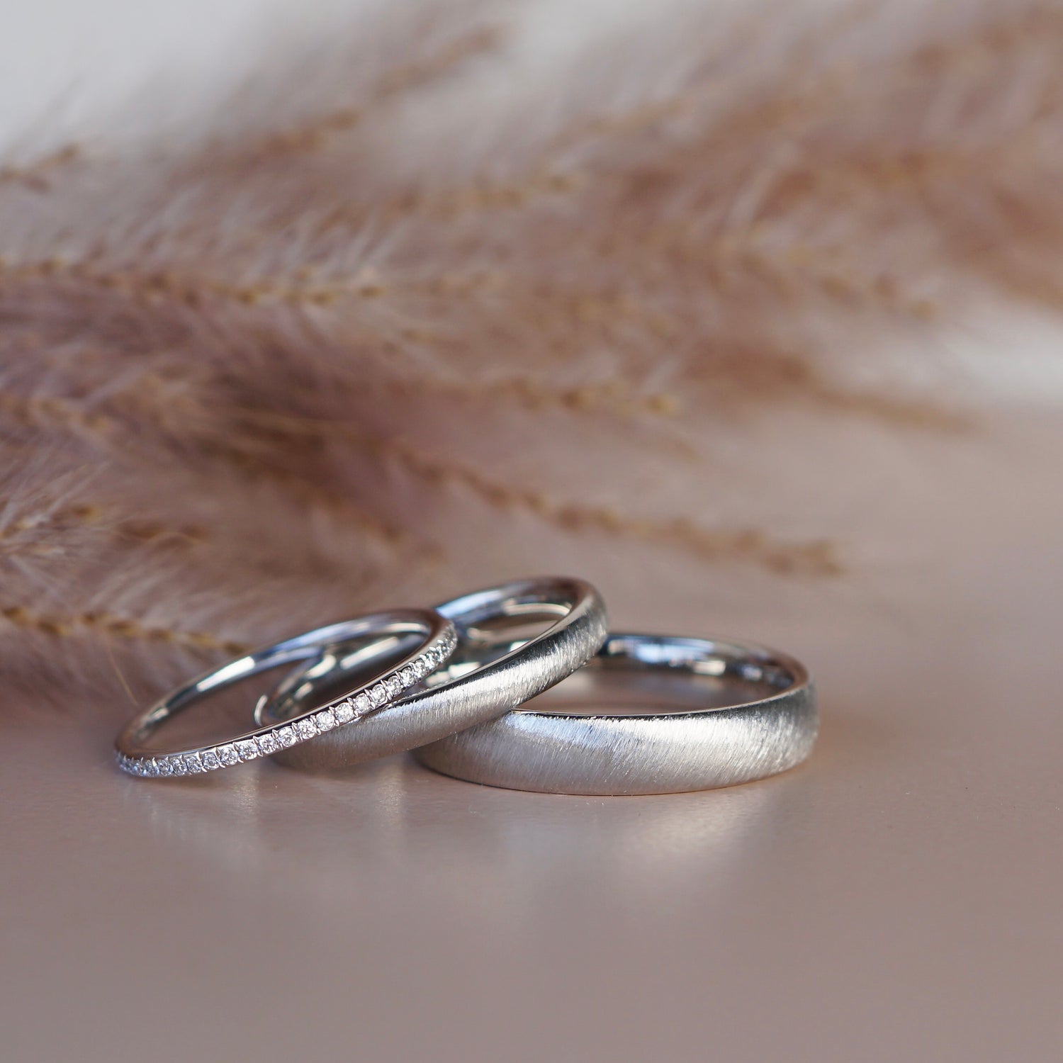 Eheringe mit samtiger Oberfläche und Diamantring aus Platin.