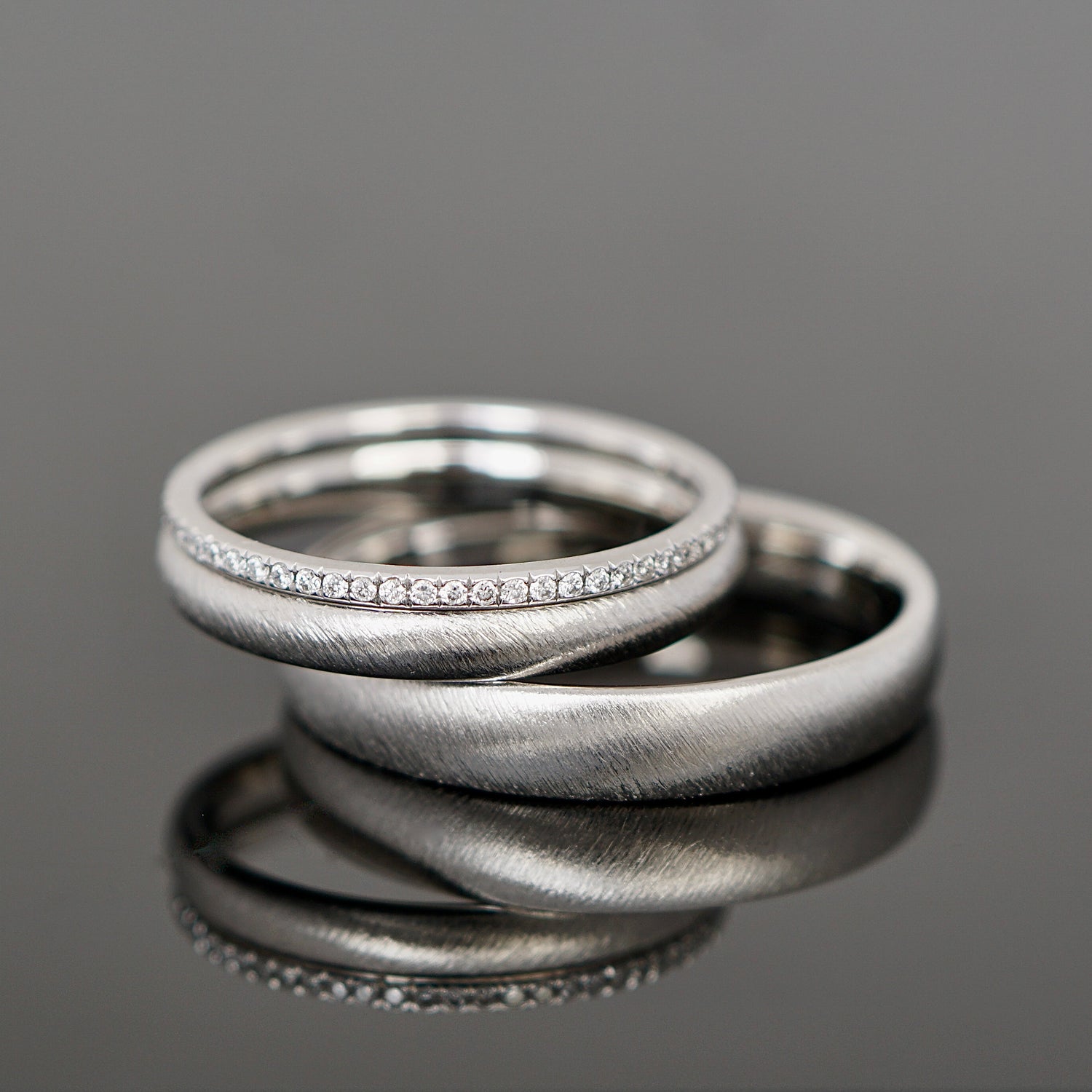 Gebürstete Eheringe aus Platin mit einem Brillantring als Vorsteckring.