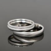 Gebürstete Eheringe aus Platin mit einem Brillantring als Vorsteckring.