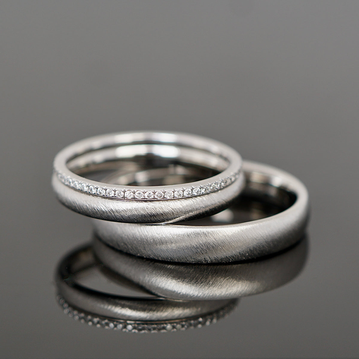 Gebürstete Eheringe aus Platin mit einem Brillantring als Vorsteckring.